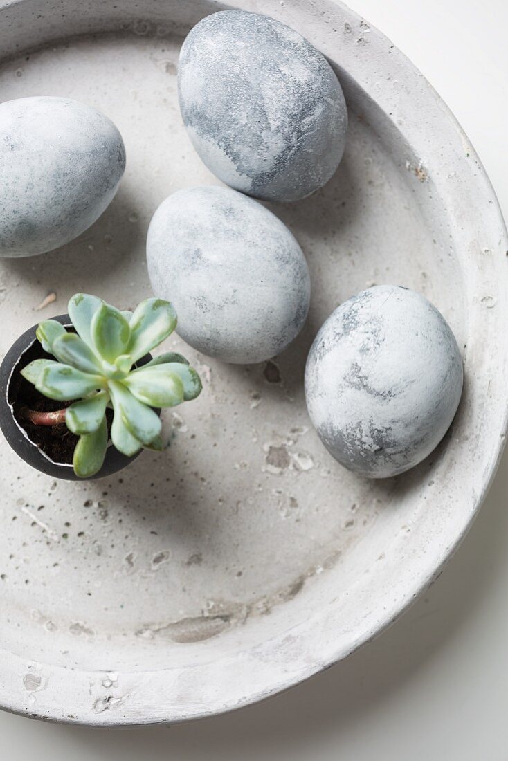 Easter eggs painted with stone effects in concrete bowl