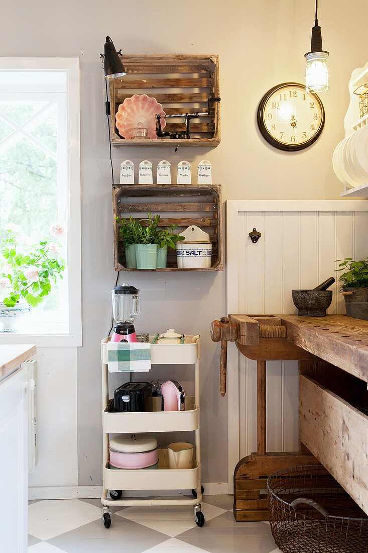 Old wooden crates used as wall-mounted shelving above serving trolley in country-house kitchen
