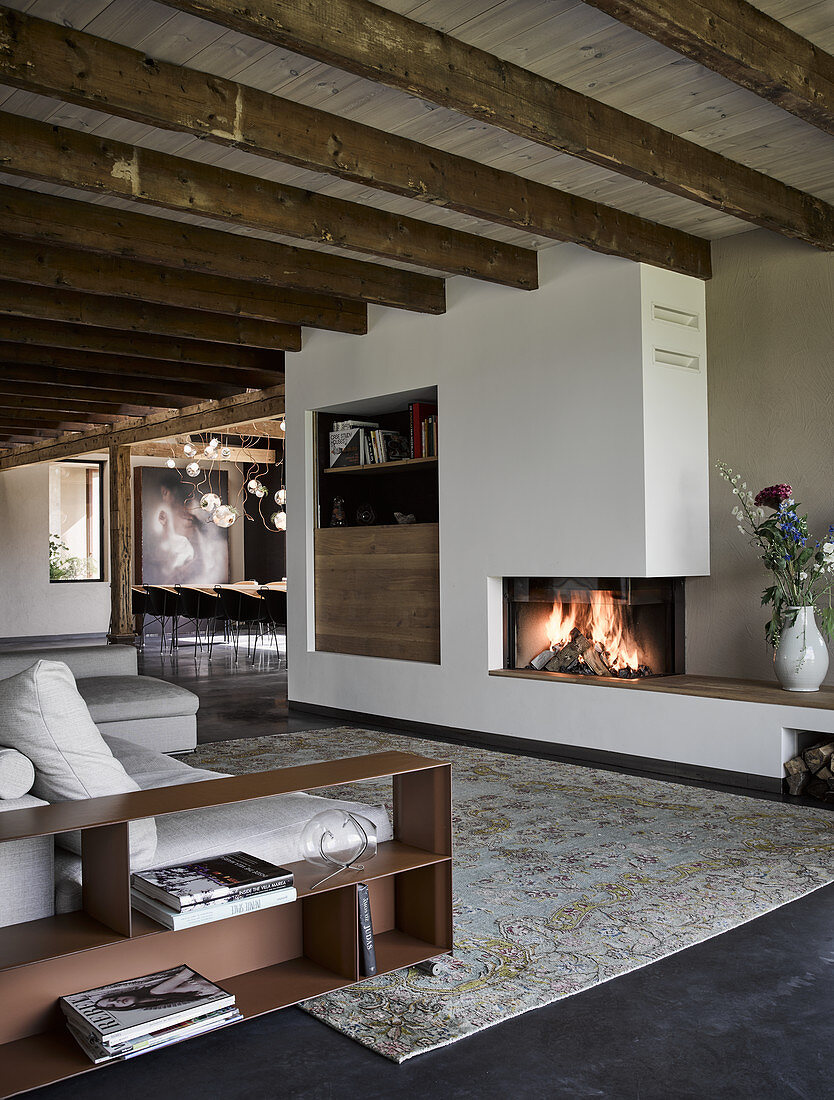 Elegante Lounge mit Kamin und rustikalen Holzbalken