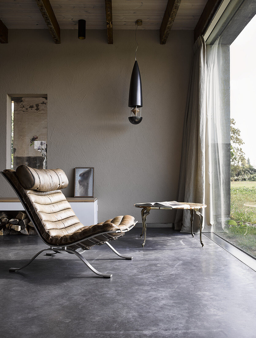 Classic chair with leather upholstery on concrete floor next to glass wall