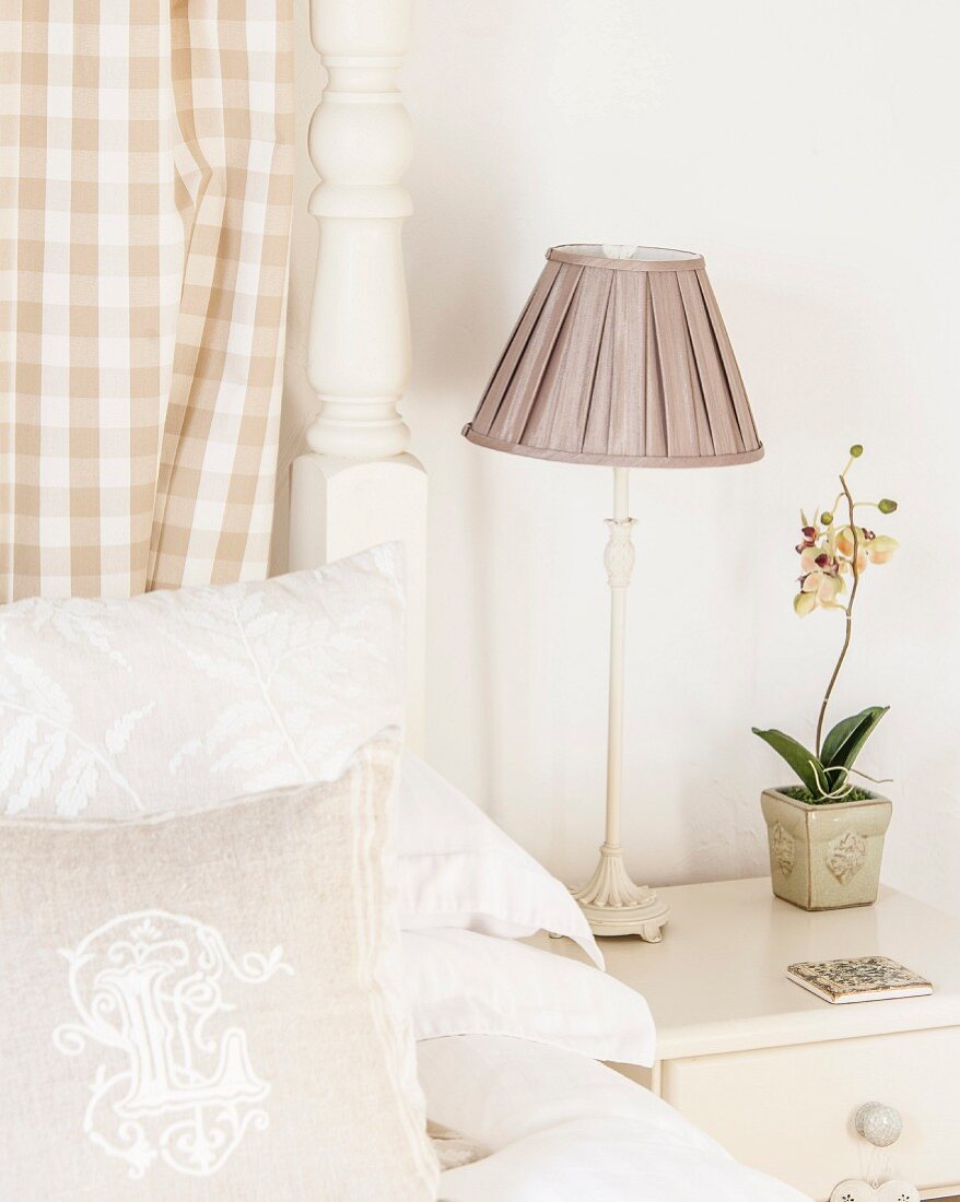 Bedside lamp with ruched lampshade next to orchid