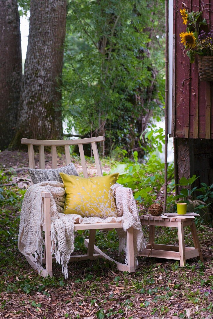 Cushions and blanket on comfortable wooden rocking chair outside wooden hut