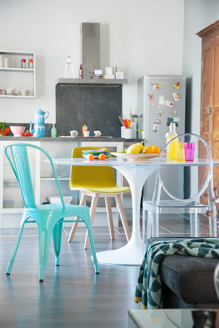Runder Esstisch mit verschiedenen Stühlen vor der offenen Küche