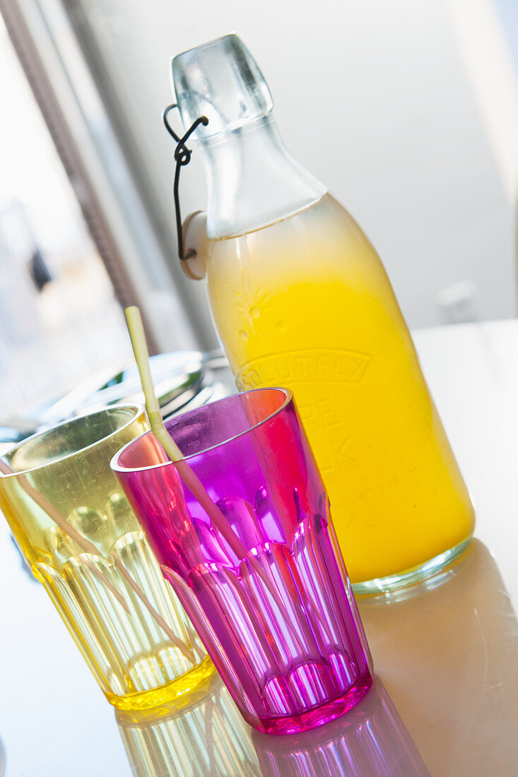 Pinkes und gelbes Glas vor einer Flasche mit Limonade