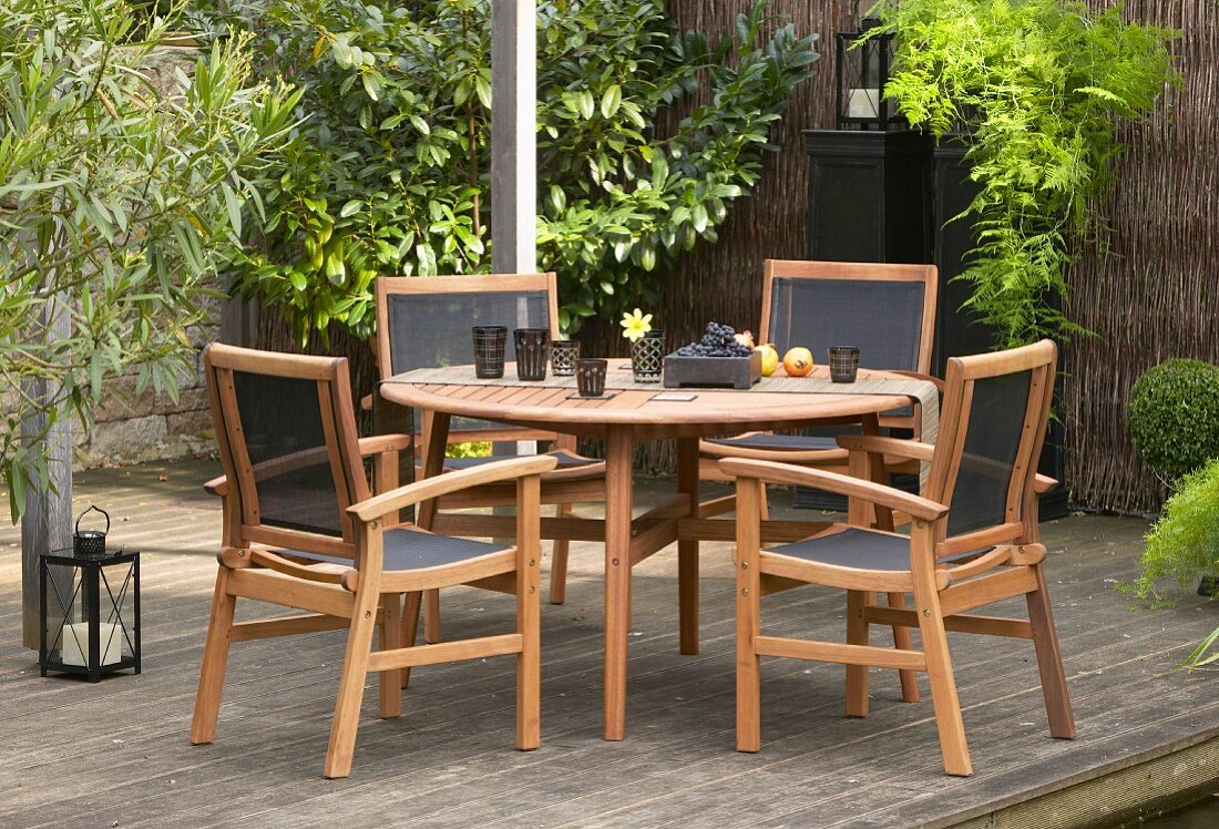 Outdoormöbel mit rundem Tisch auf begrünter Holzterrasse