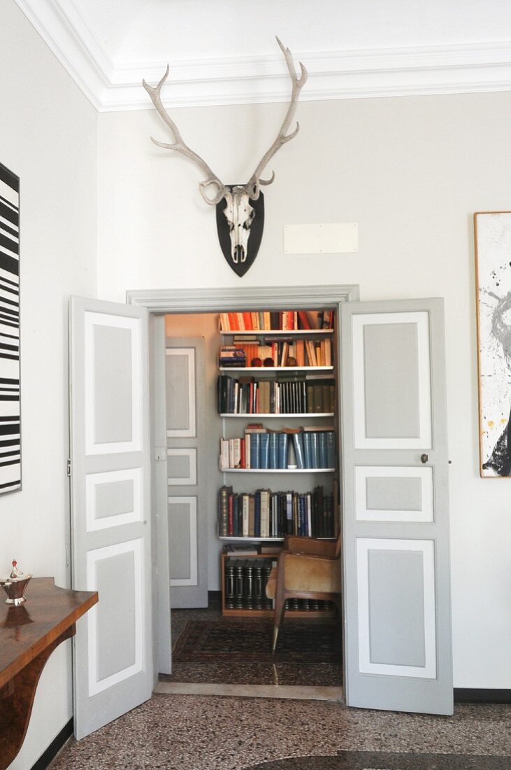 Hunting trophy above open double doors with view of bookcase