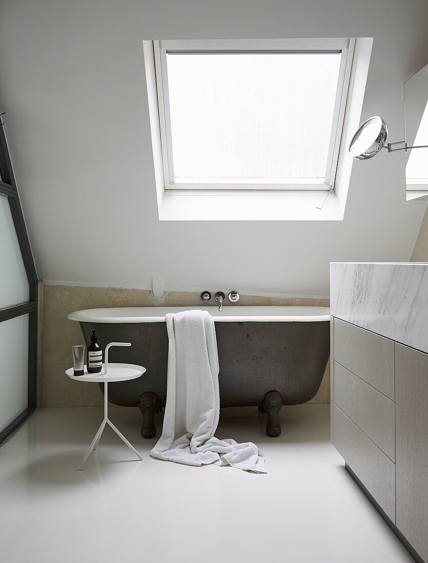 Free-standing bathtub under sloping skylight and against crooked knee wall