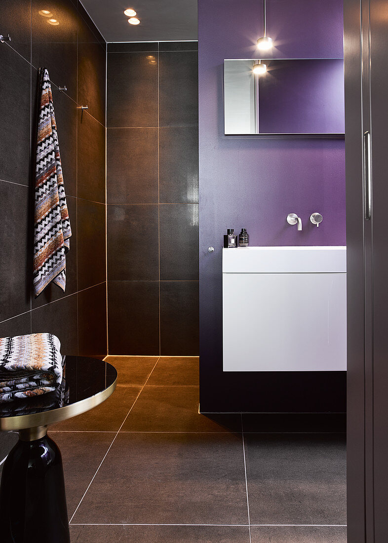 Modernes Bad mit schwarzen Fliesen und violetter Wand