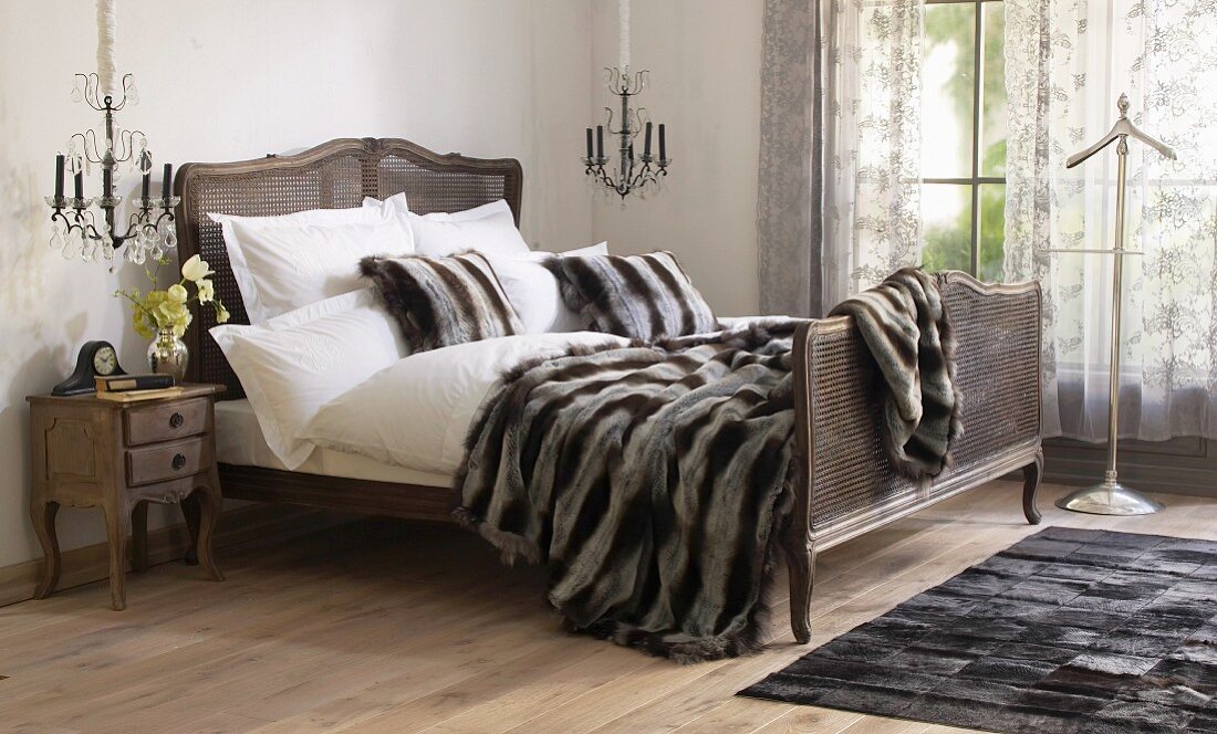 Patchwork fur rug next to French bed with fur blanket