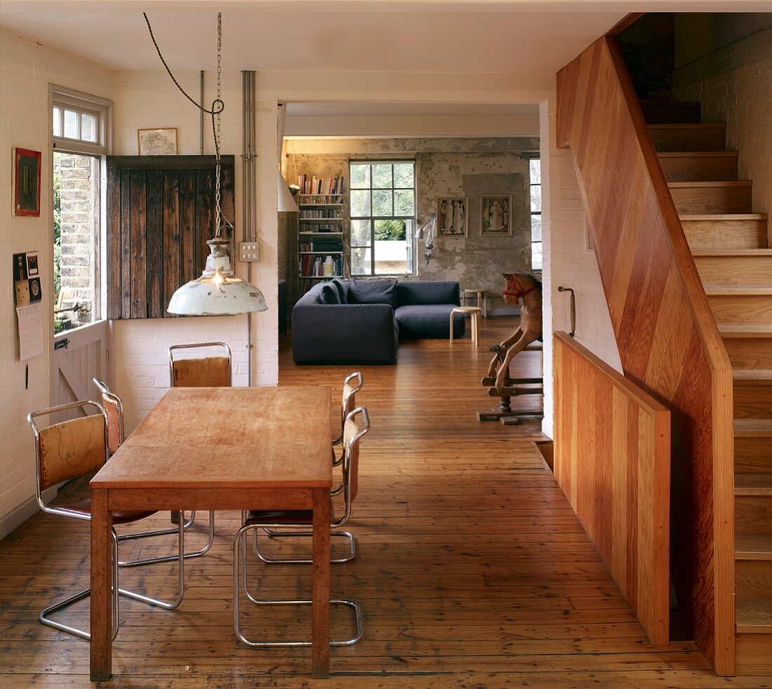 Table and cantilever chairs on wooden floor in dining room with staircase to one side