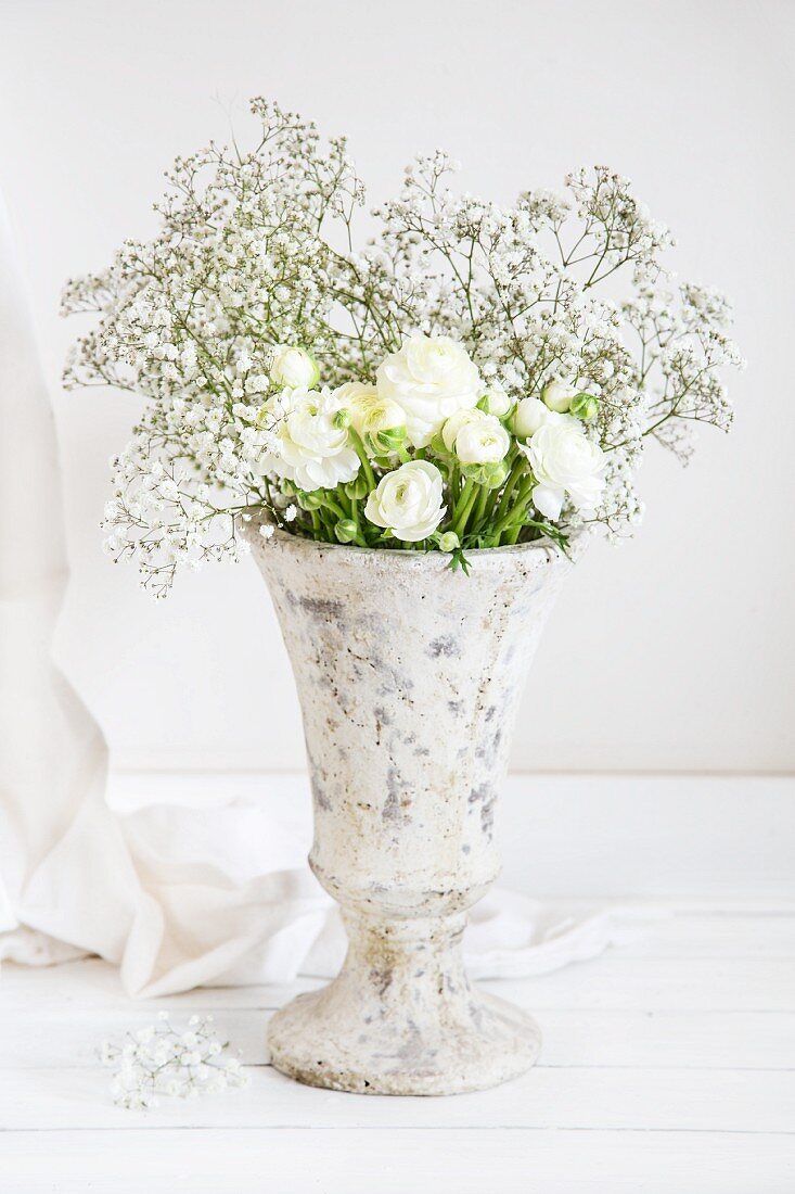 White ranunculus and gypsophila in stone vase