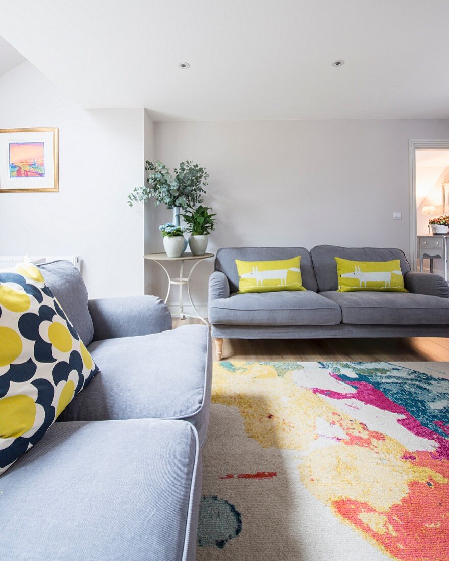 Grey sofas paired with colourful rug and scatter cushions in living room