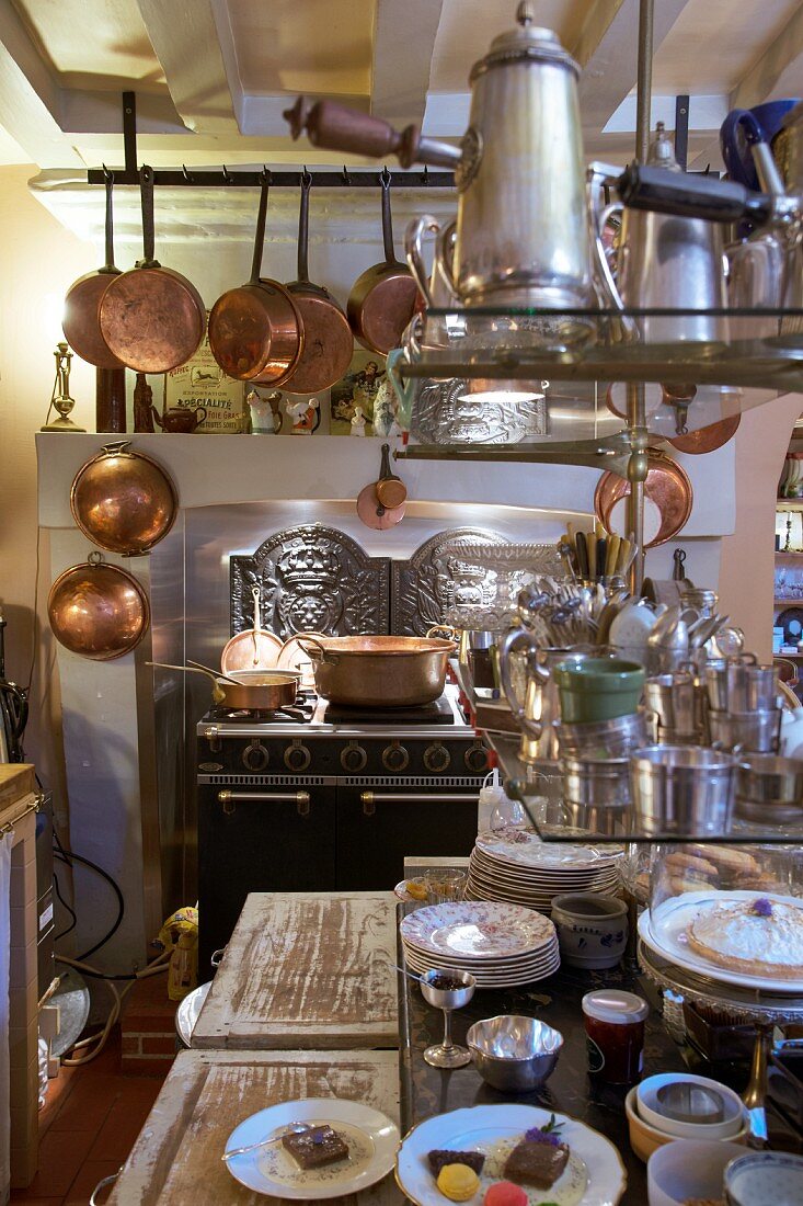 Küche mit antikem Herd, Kupfertöpfen und offenen Regalen