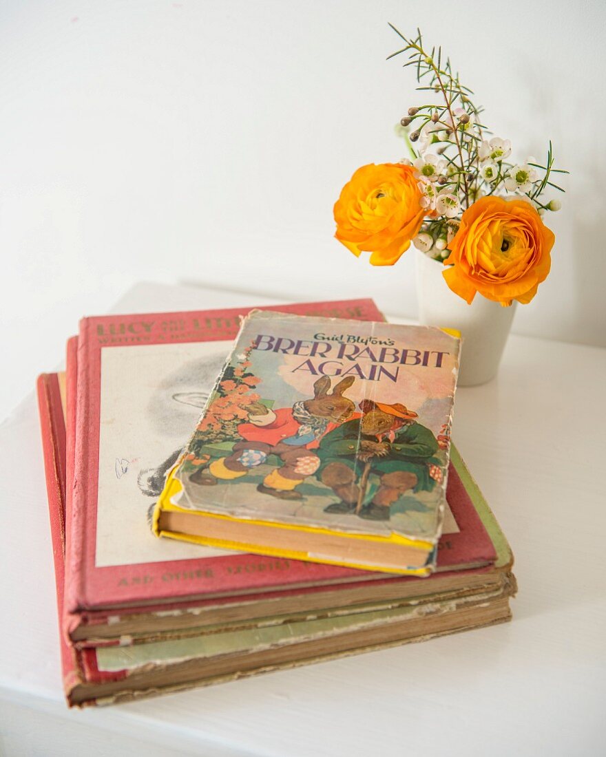 Retro Kinderbücher neben Blumensträußchen auf weißem Kindertisch