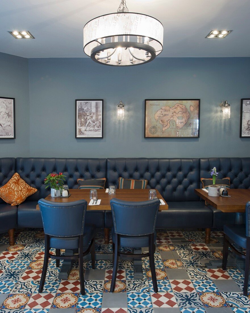 Leather benches and chairs on ornamental floor tiles in retro restaurant in shades of blue