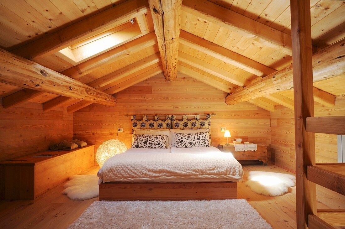 Schlafzimmer unter dem Dach in einem Holzhaus