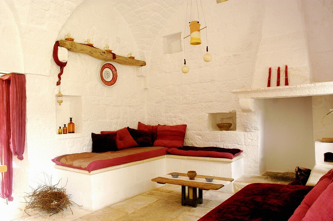 Weiß getünchte Lounge mit roten Farbakzenten in einem renoviertem Trullo