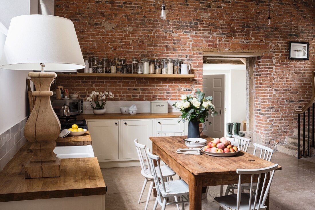 Rustikaler Holztisch in offener Küche mit Ziegelwand