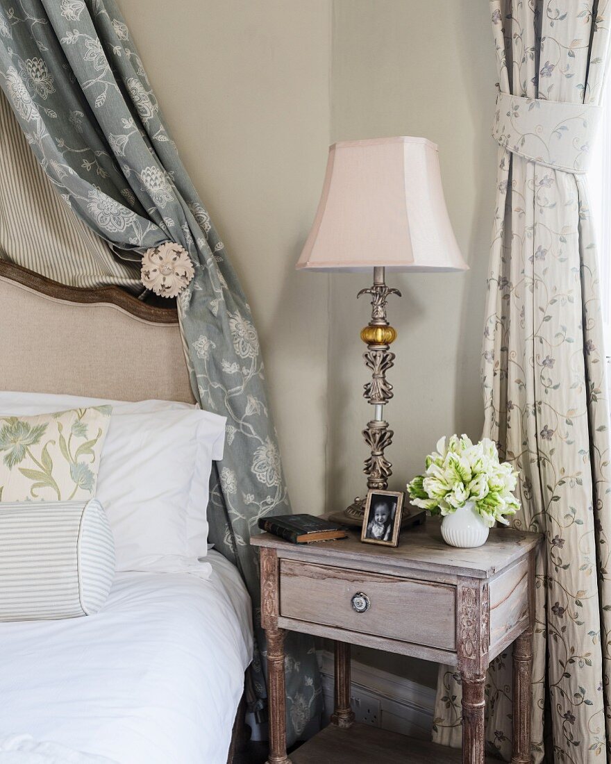 Eleganter Nachttisch mit Lampe und Foto und Blume im Schlafzimmer