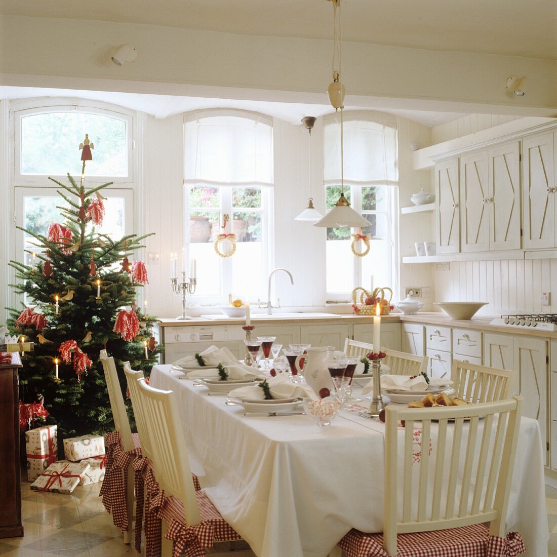 Festively set table and Christmas tree in country-house kitchen