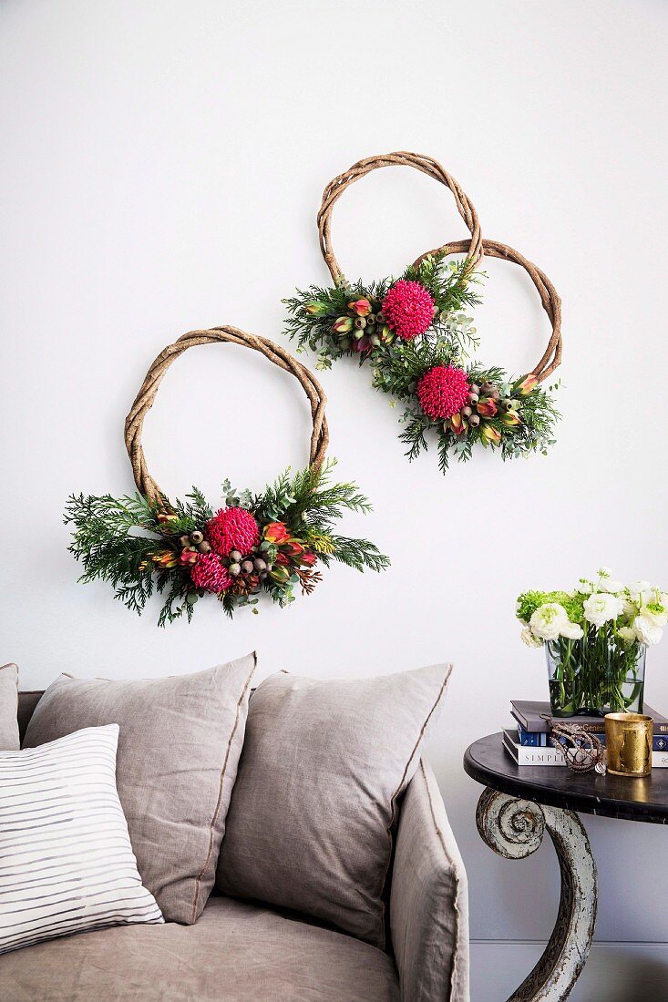 Three wreaths of curved branches with flowers above the sofa