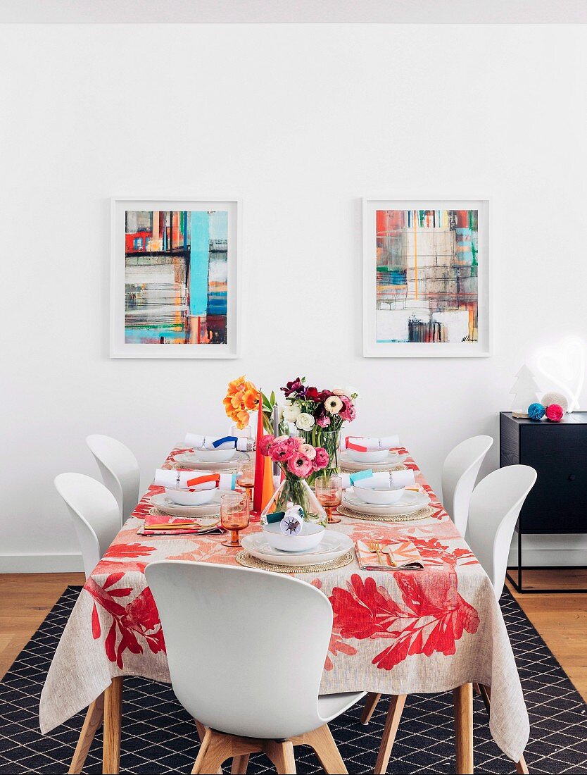Colorfully laid table with bouquets of flowers in front of colorful pictures