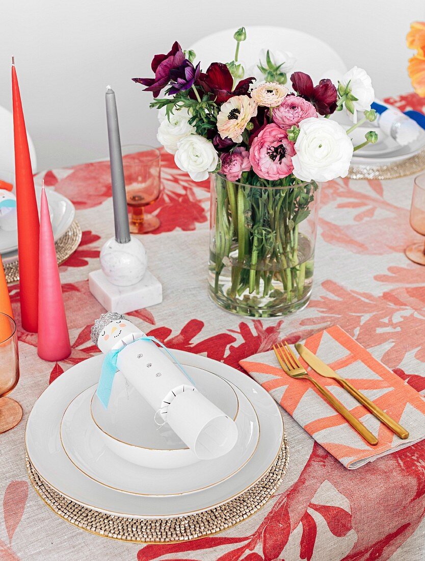 Bunt gedeckter Tisch mit Blumenstrauß und farbigen Kerzen