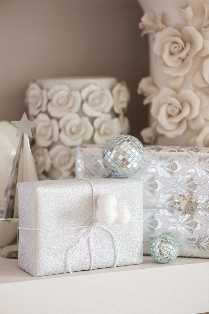 Gifts wrapped in white shimmering paper decorated with small disco balls
