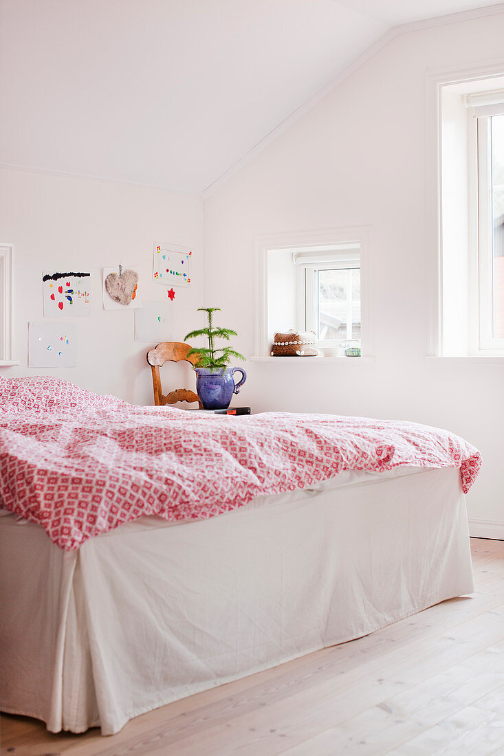 Rot-weiße Bettwäsche auf dem Bett mit Husse im weißen Schlafzimmer