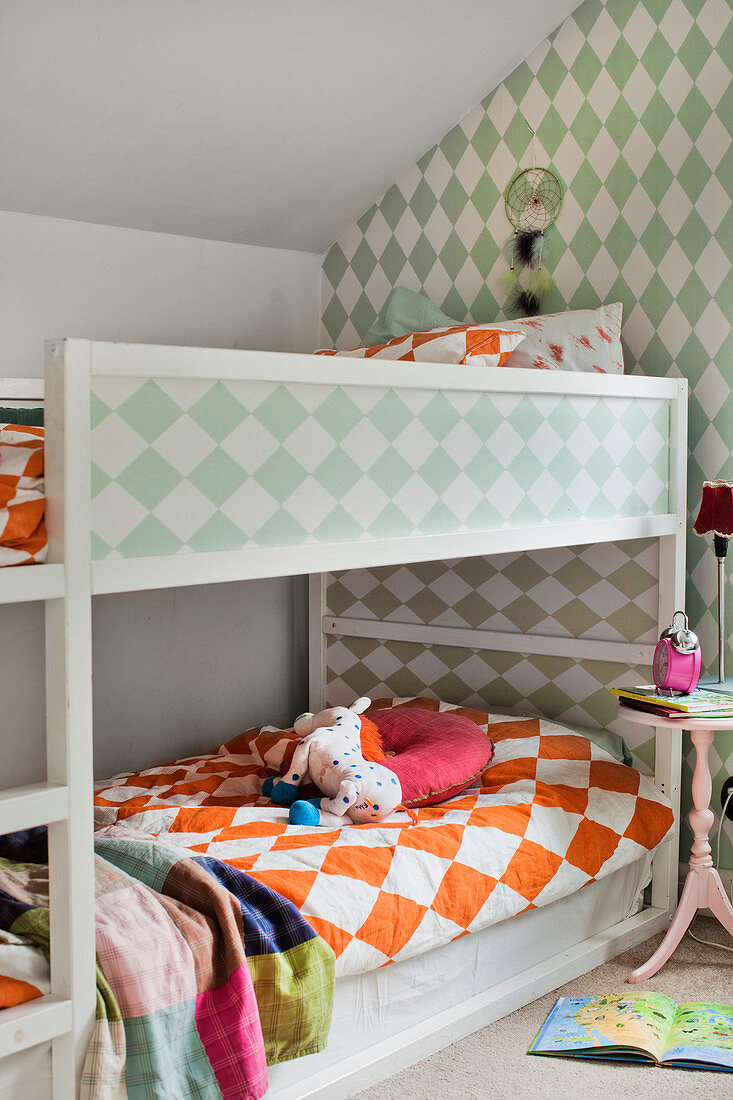 Bunk beds and green and white patterned wallpaper in children's bedroom