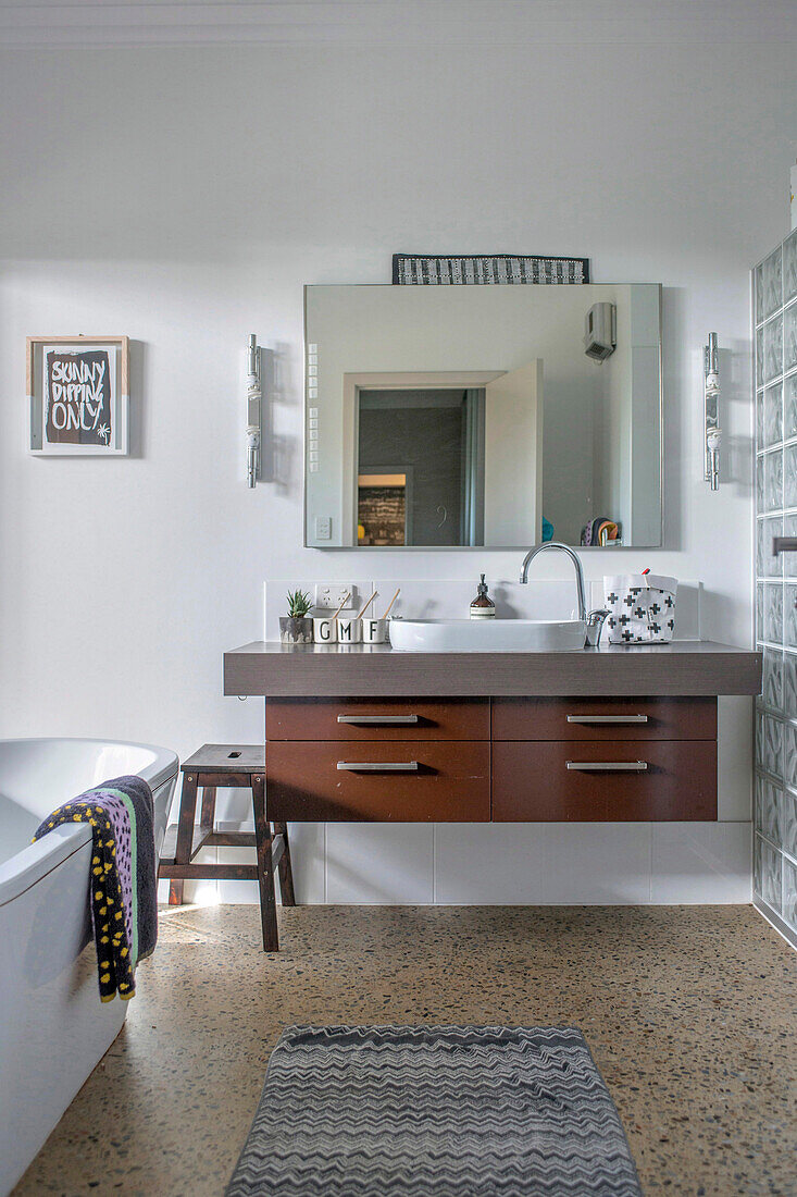 Modernes Badezimmer mit Wandspiegel, Holzwaschtisch und grauem Teppich