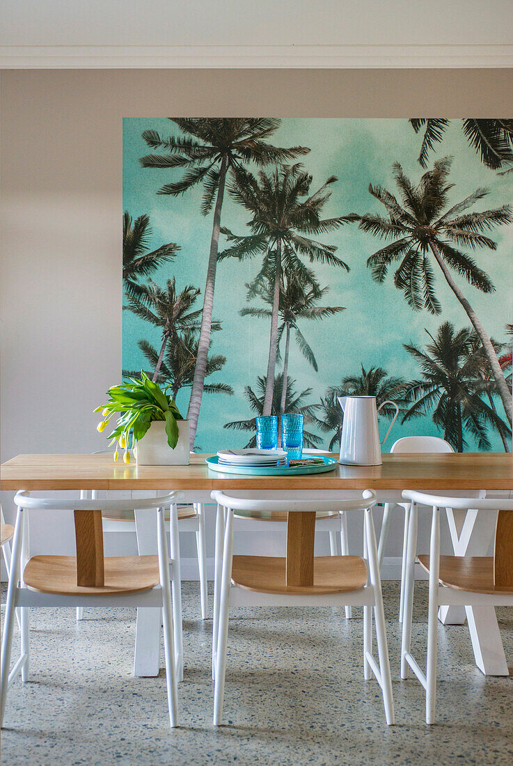 Bright dining room with palm tree mural and wooden table