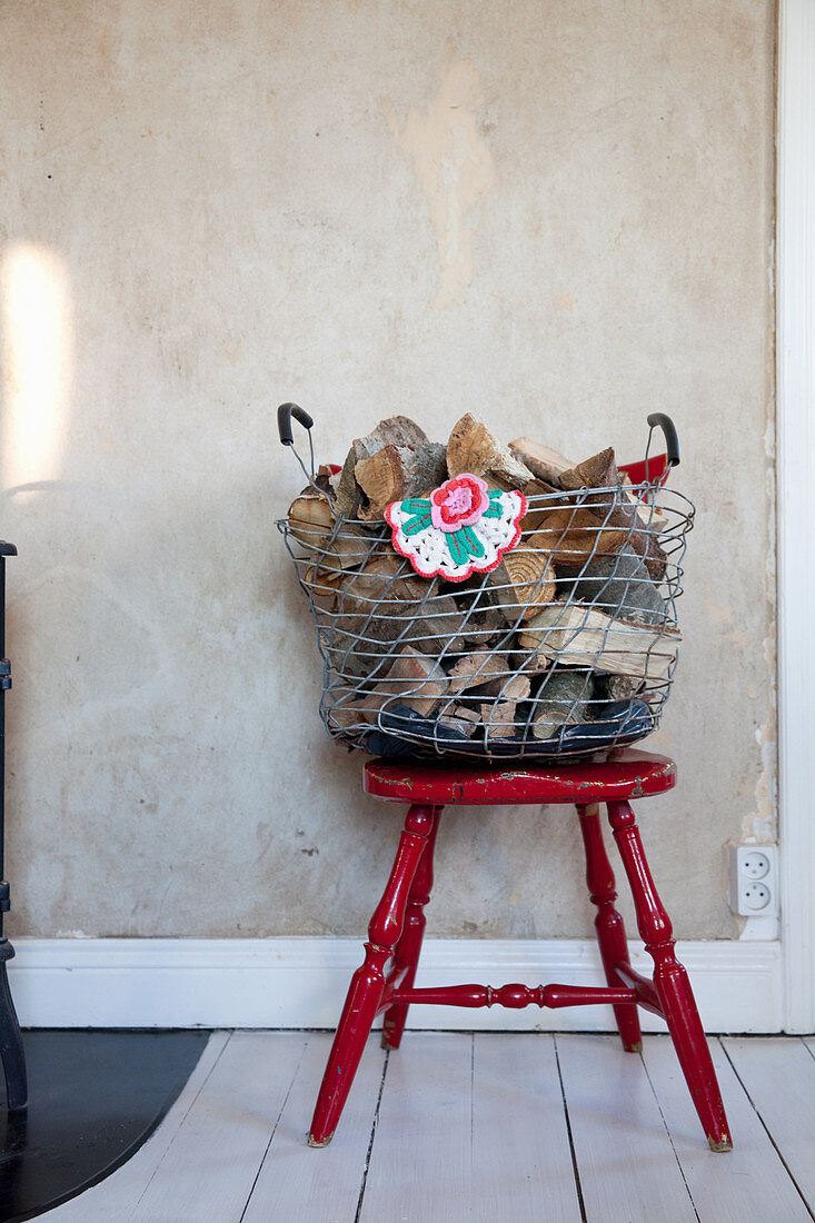 Firewood in wire basket on old red chair