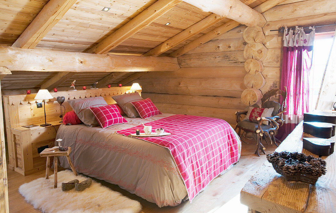 Bett mit Karodecke im rustikalen Schlafzimmer in einem Blockhaus