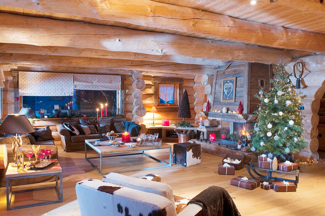 Christmas tree and arrangements of candles in living room of log cabin