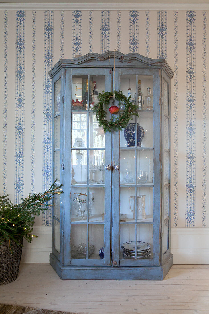 Blue, shabby-chic display case against blue-and-white country-house wallpaper