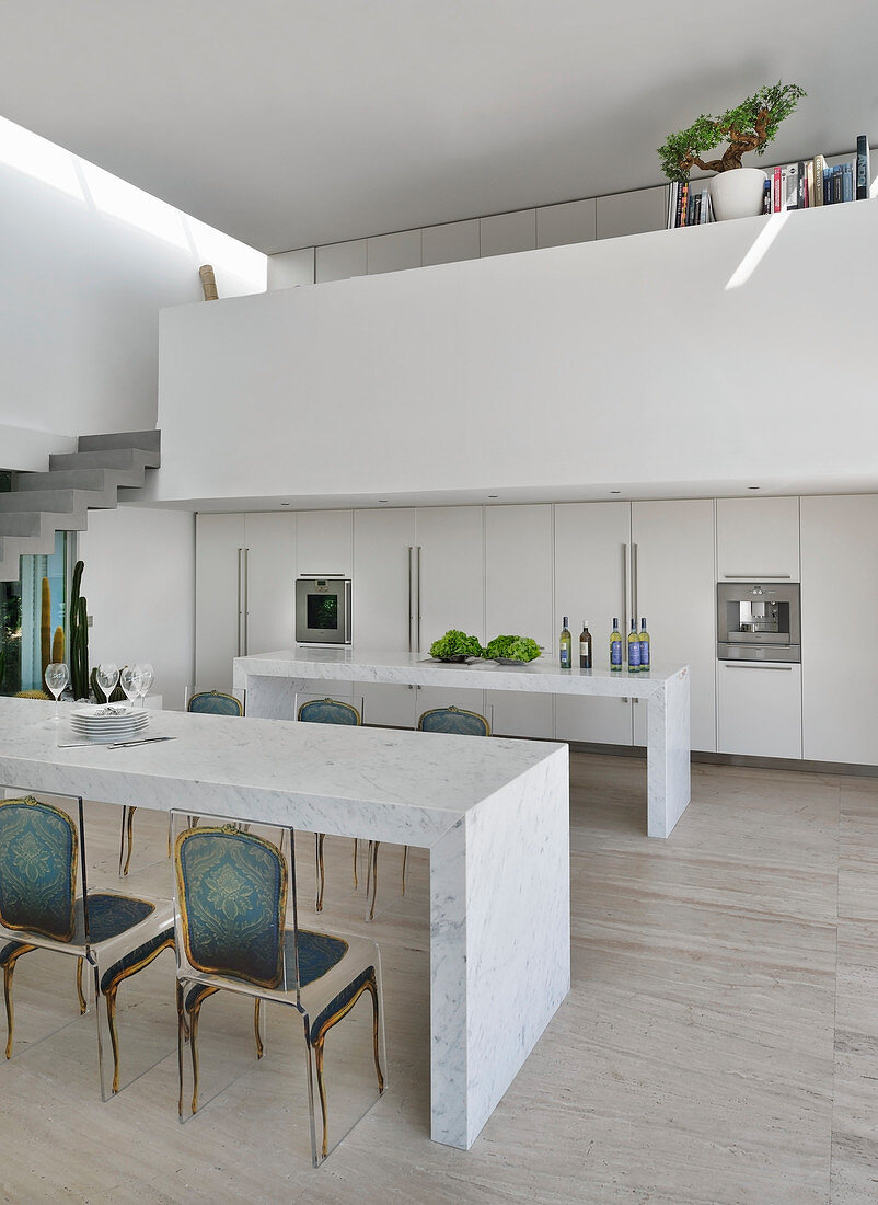 Marmortisch vor minimalistischer offener Küche unter der Galerie