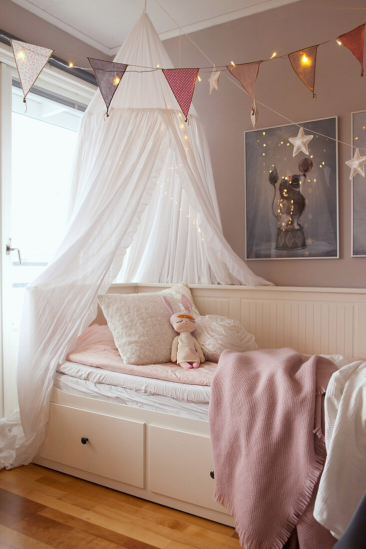 Canopy, garland and fairy lights over comfortable couch