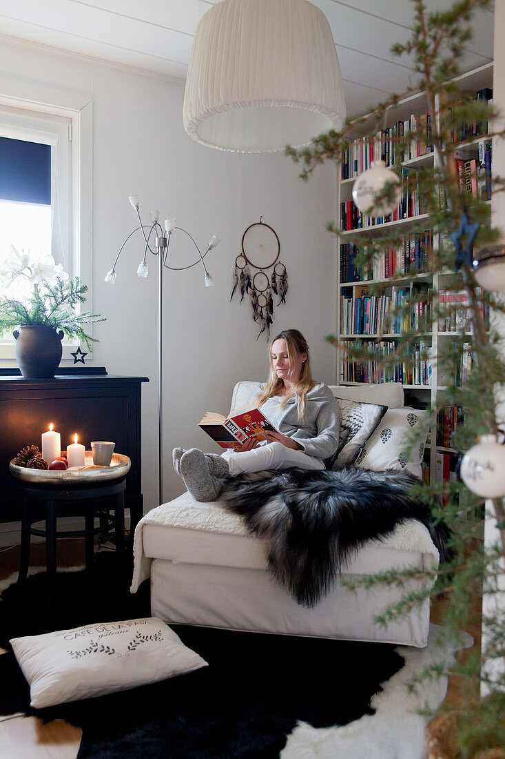 Woman seated on récamier reading in cosy living room