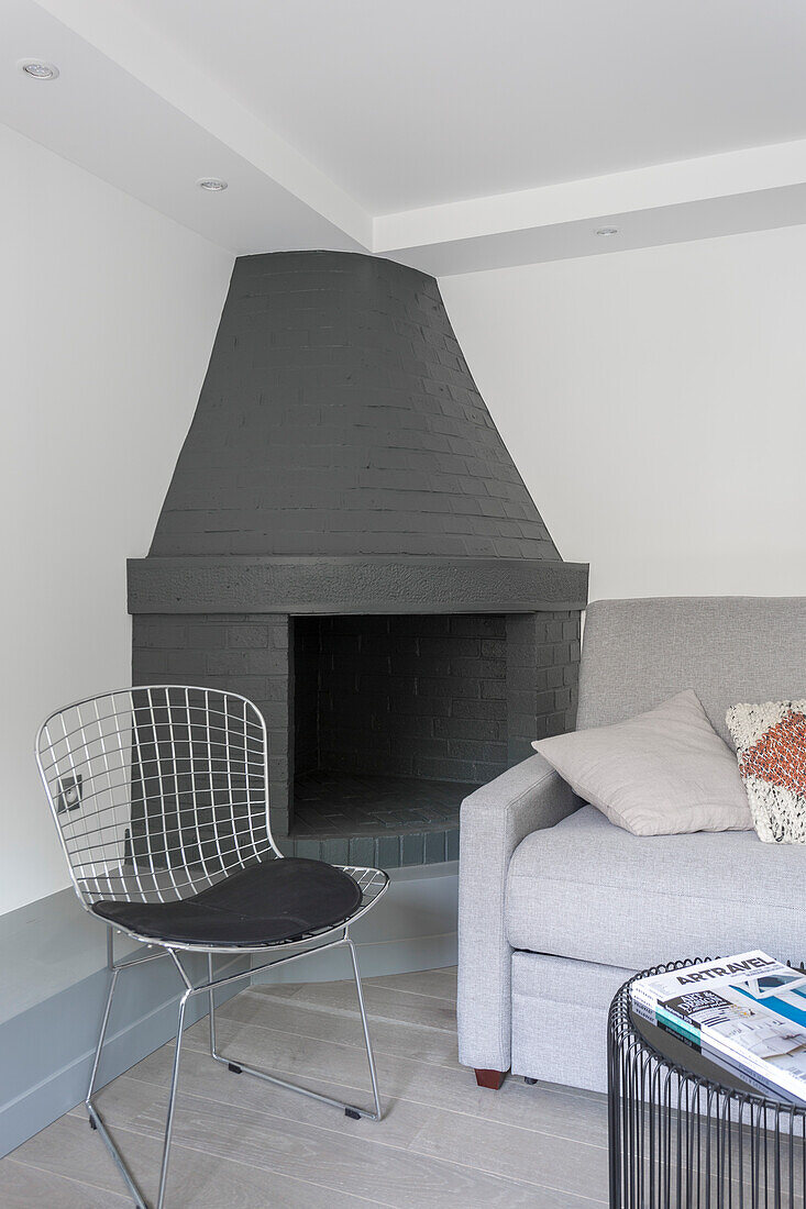 Corner fireplace, classic wire chair and grey sofa in living room