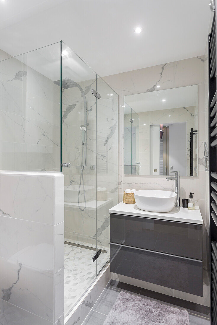 Washstand with countertop sink and shower with glass screen in bathroom