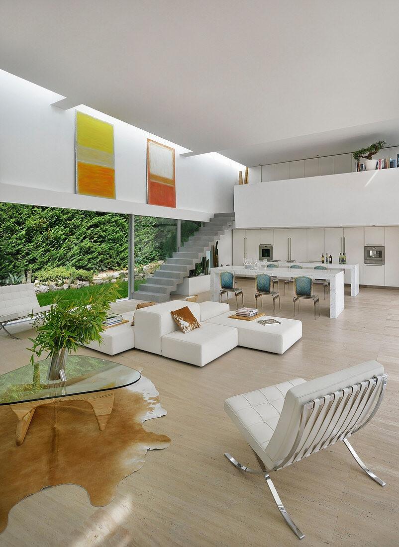 White, modern, open-plan interior with glass wall leading to garden