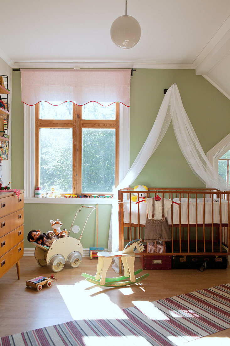 Gitterbett mit Baldachin im nostalgischen Kinderzimmer mit grüner Wand