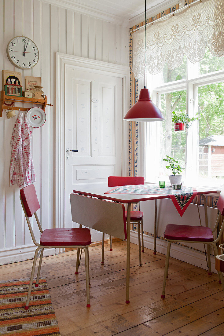 Rote Retrostühle um den Tisch vorm Fenster in der Landhausküche