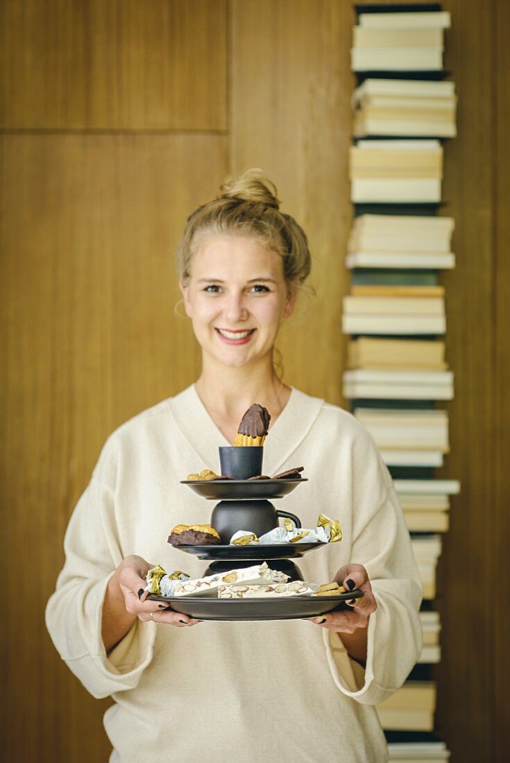 Junge Frau hält DIY-Etagere aus Tellern und Tassen