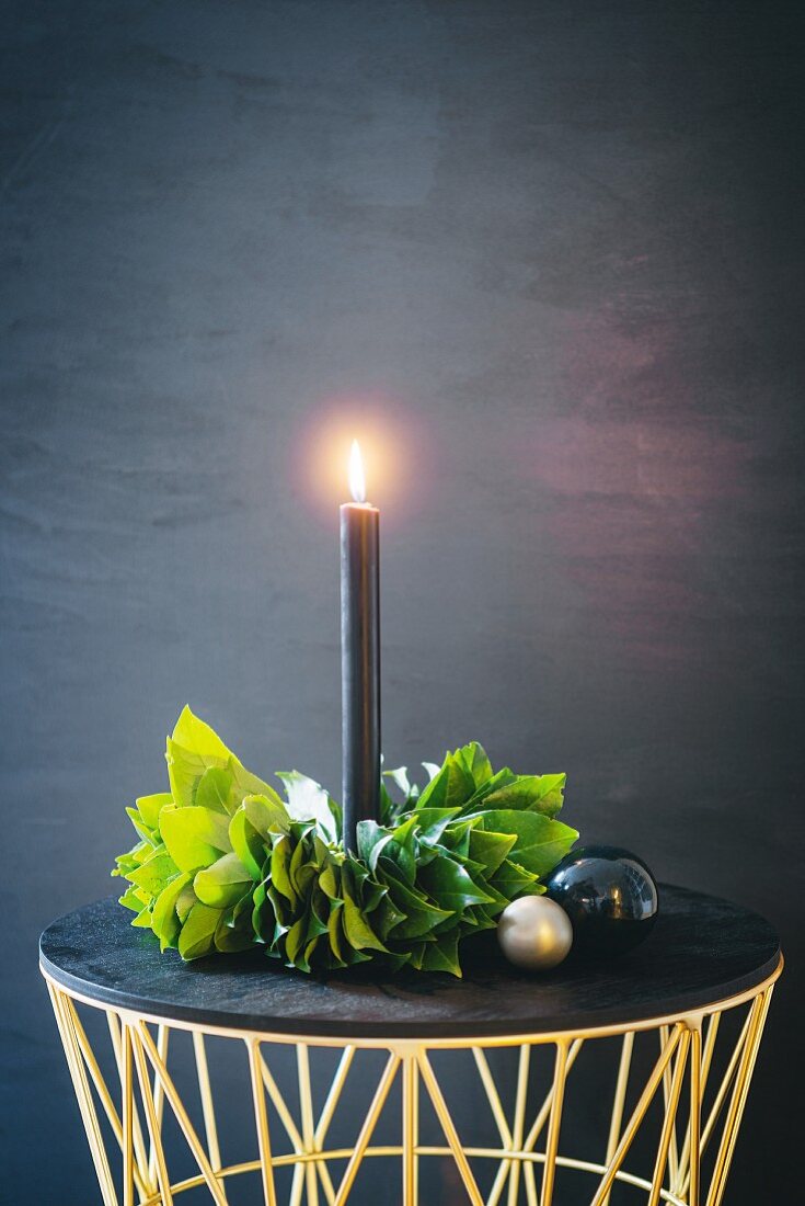 Brennende schwarze Kerze mit DIY-Blätterkranz
