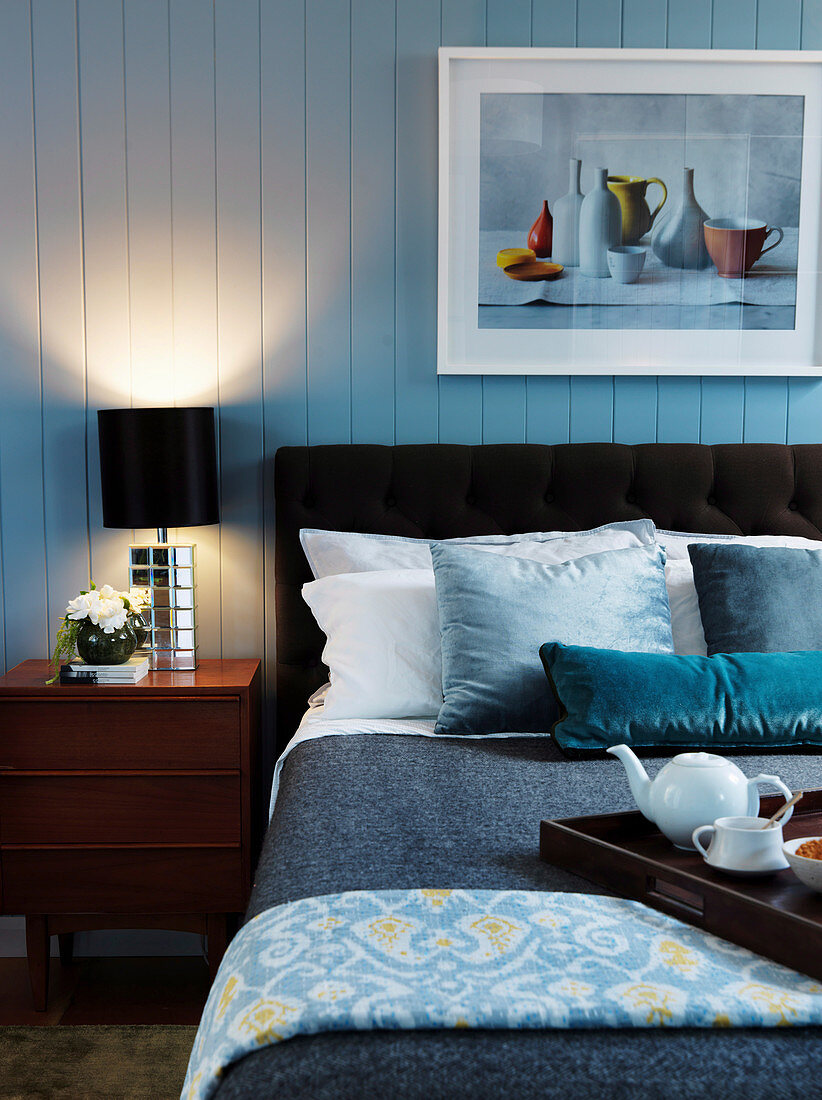Doppelbett und Nachtkästchen mit Nachttischlampe im Schlafzimmer mit Holzverkleidung