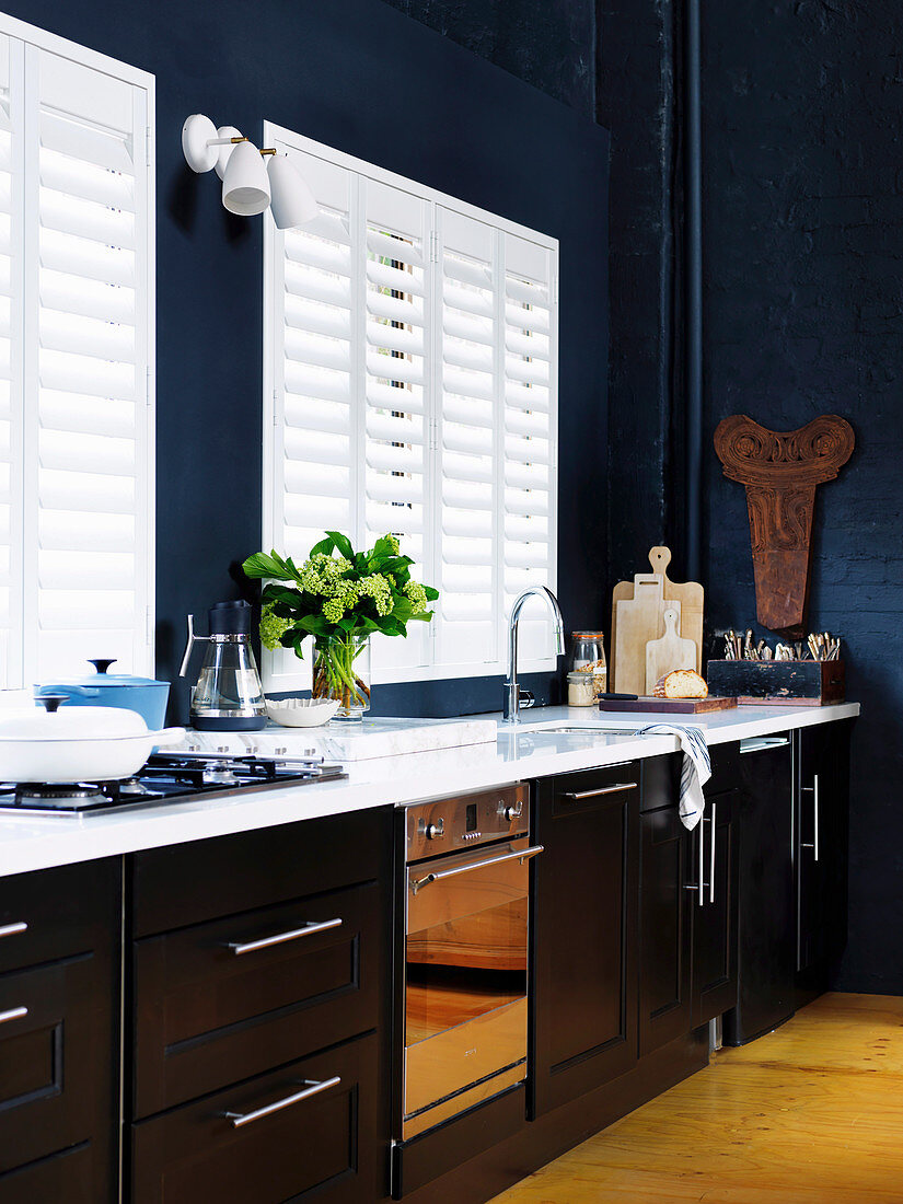Küchenzeile vor weissen Lamellenfenstern in hoher Küche mit dunkelblauer Wand