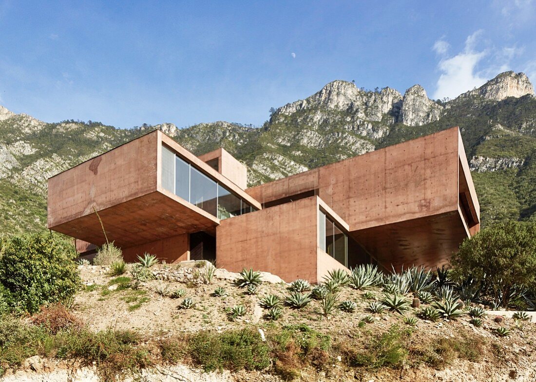 Modernes Architektenhaus aus rot gefärbtem Beton in den Bergen