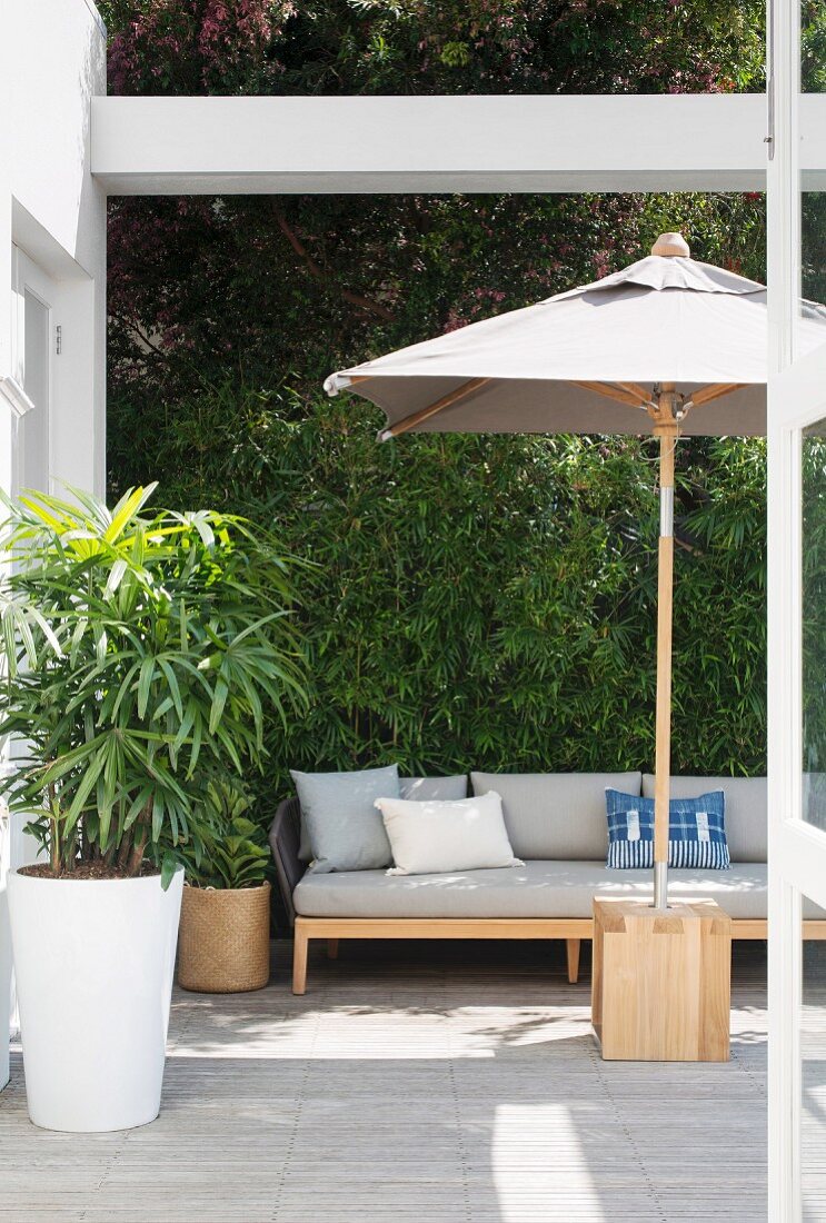 Schirm und Sitzbank auf moderner Terrasse mit begrünter Wand